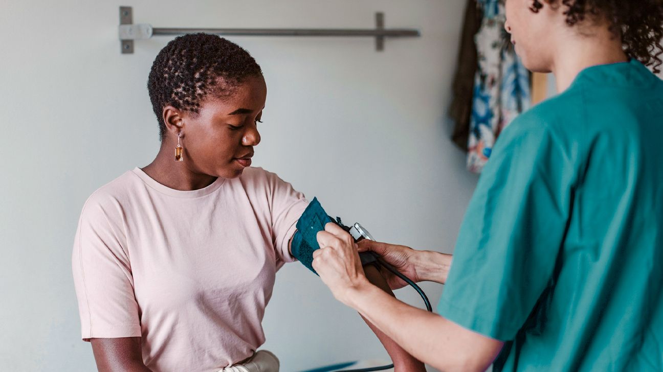 Doctor takes blood pressure reading from female patient