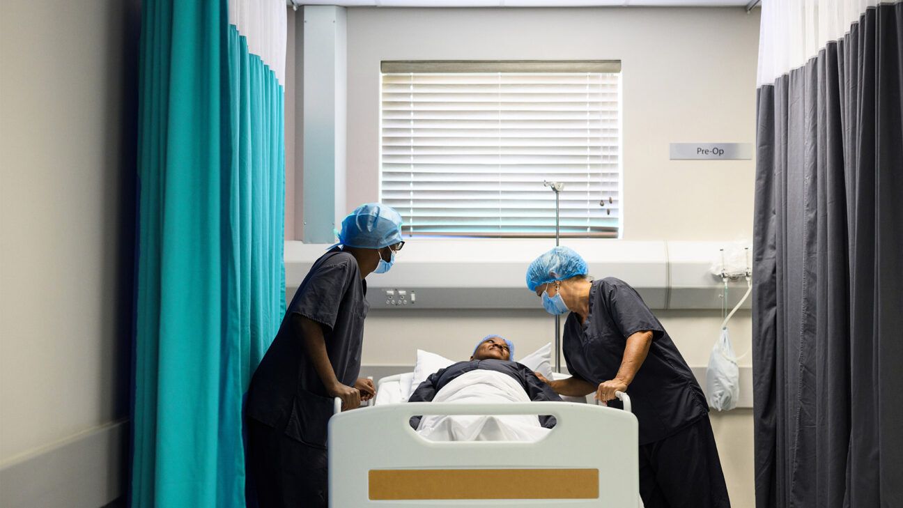 Two healthcare professionals prep a patient for surgery