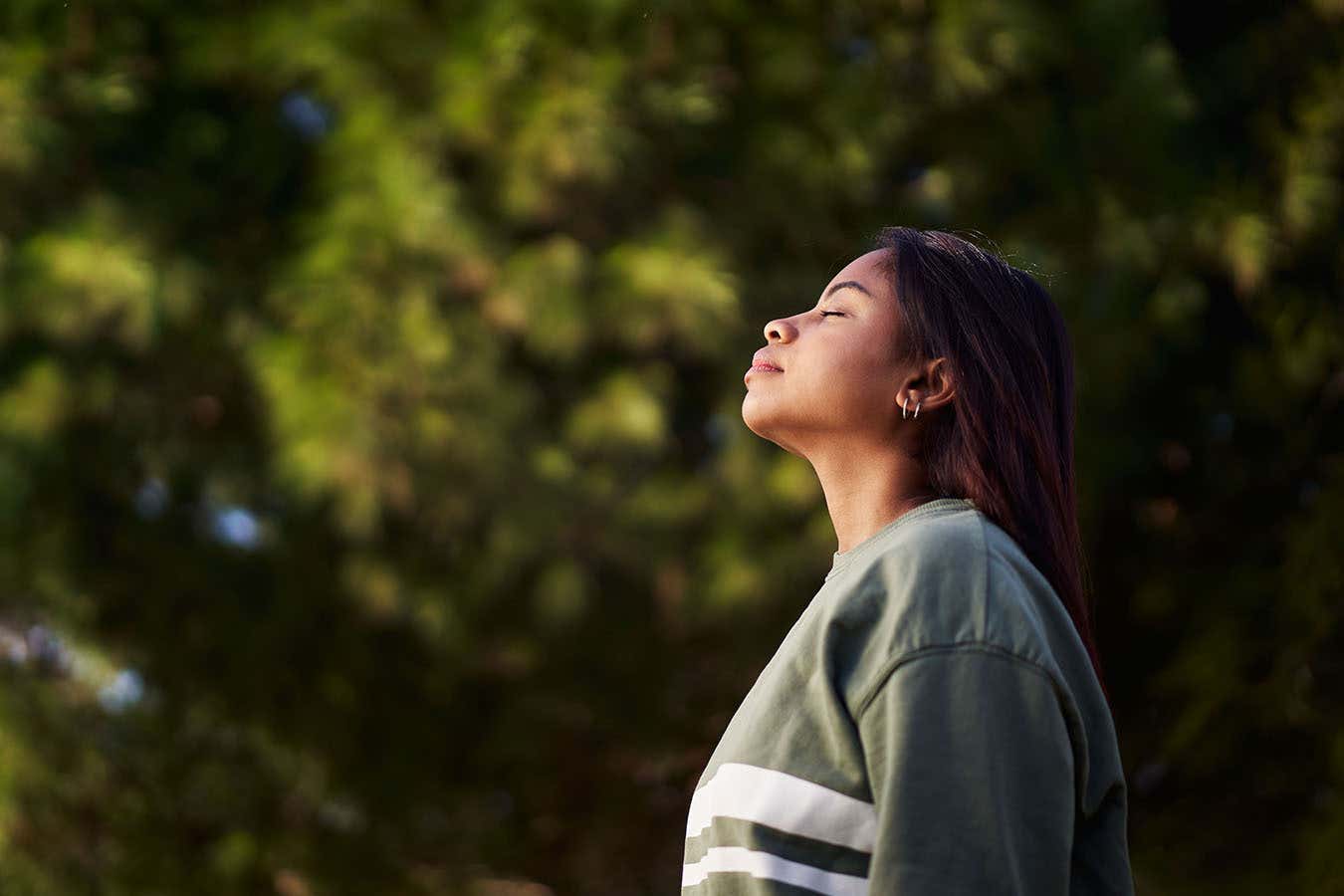 A person breathing outside with trees in the background