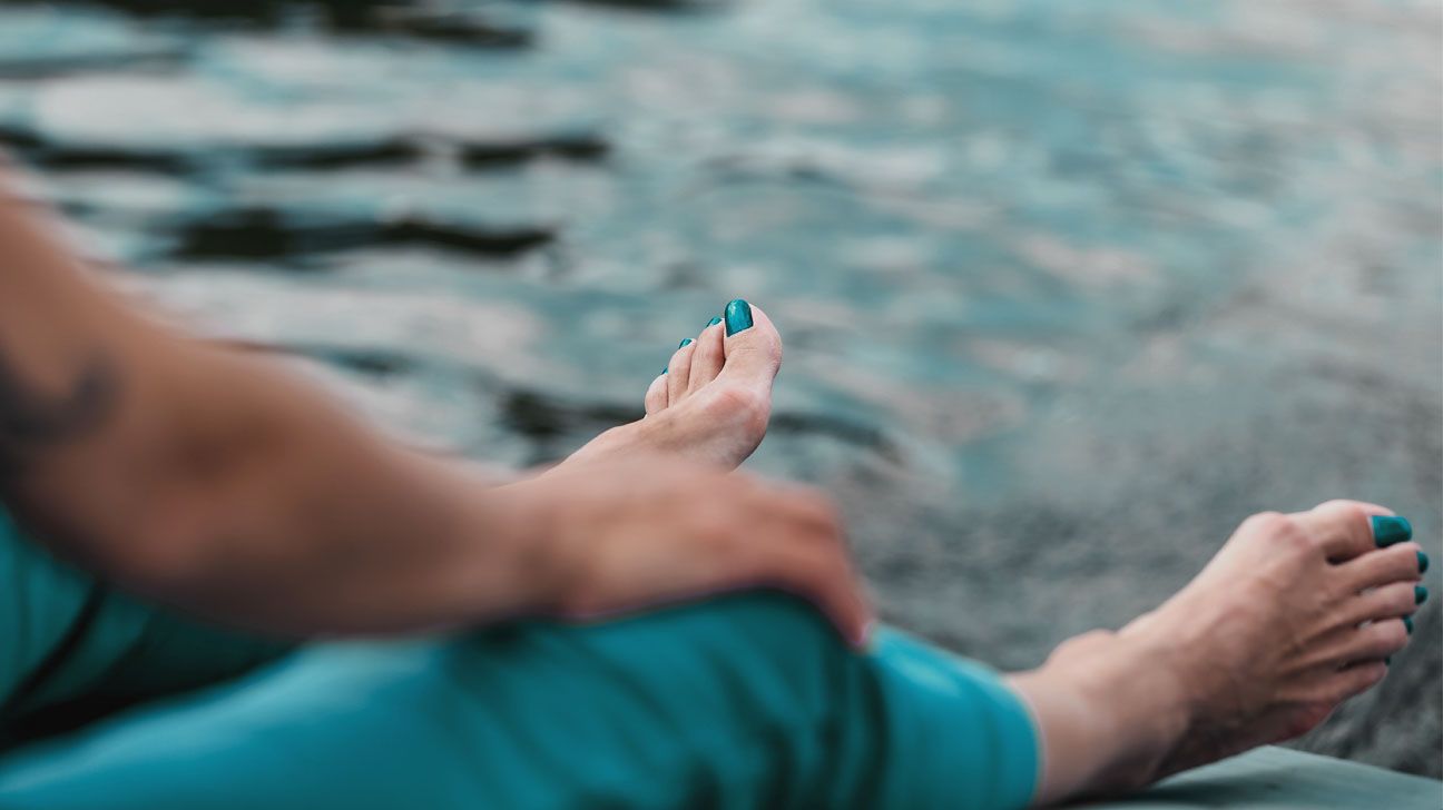 Bare feet dangling over water