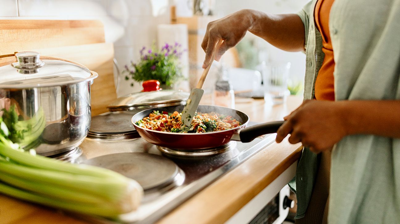 Female cooking at stove in kitchen