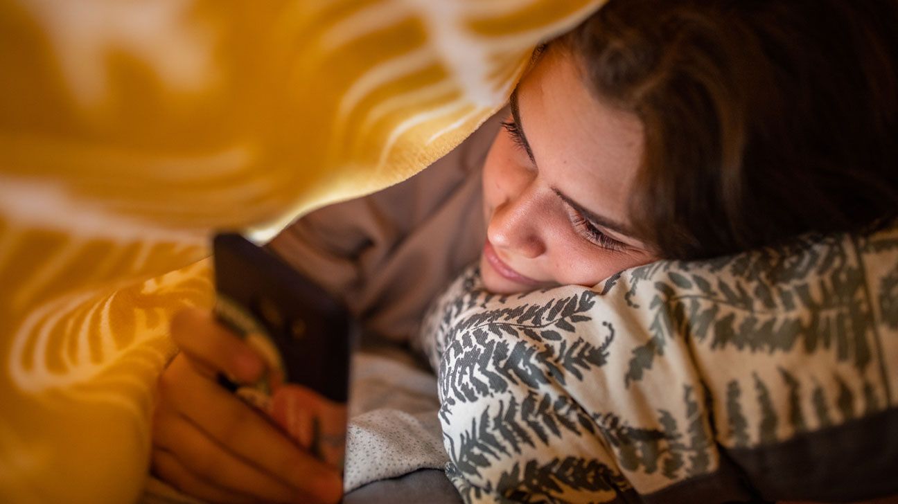 Young female on social media in bed