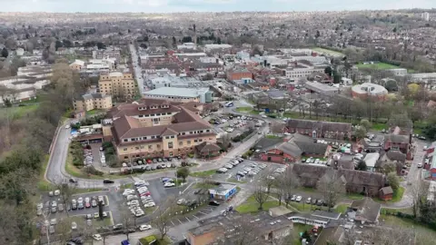 BBC A drone-image of Nottingham City Hospital with city skyline in the background. Car parks and surrounding buildings can be seen in the aerial image