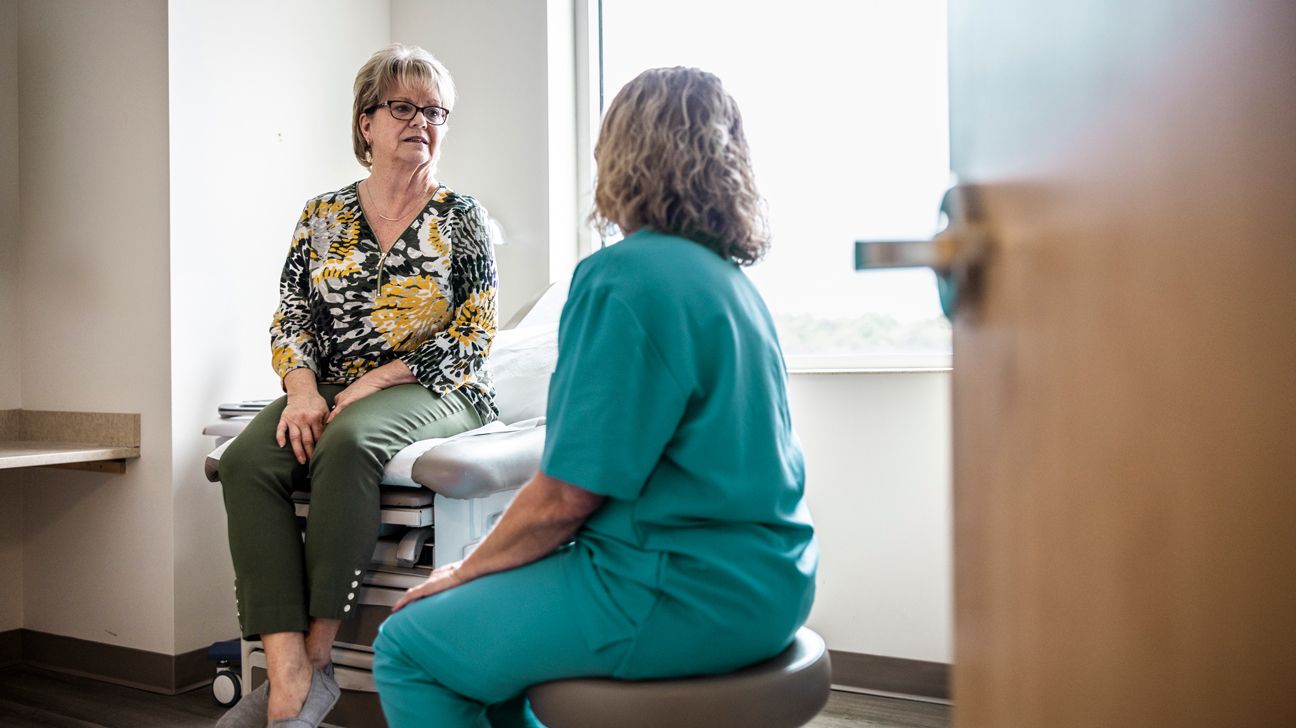 Female patient talks with doctor in exam room