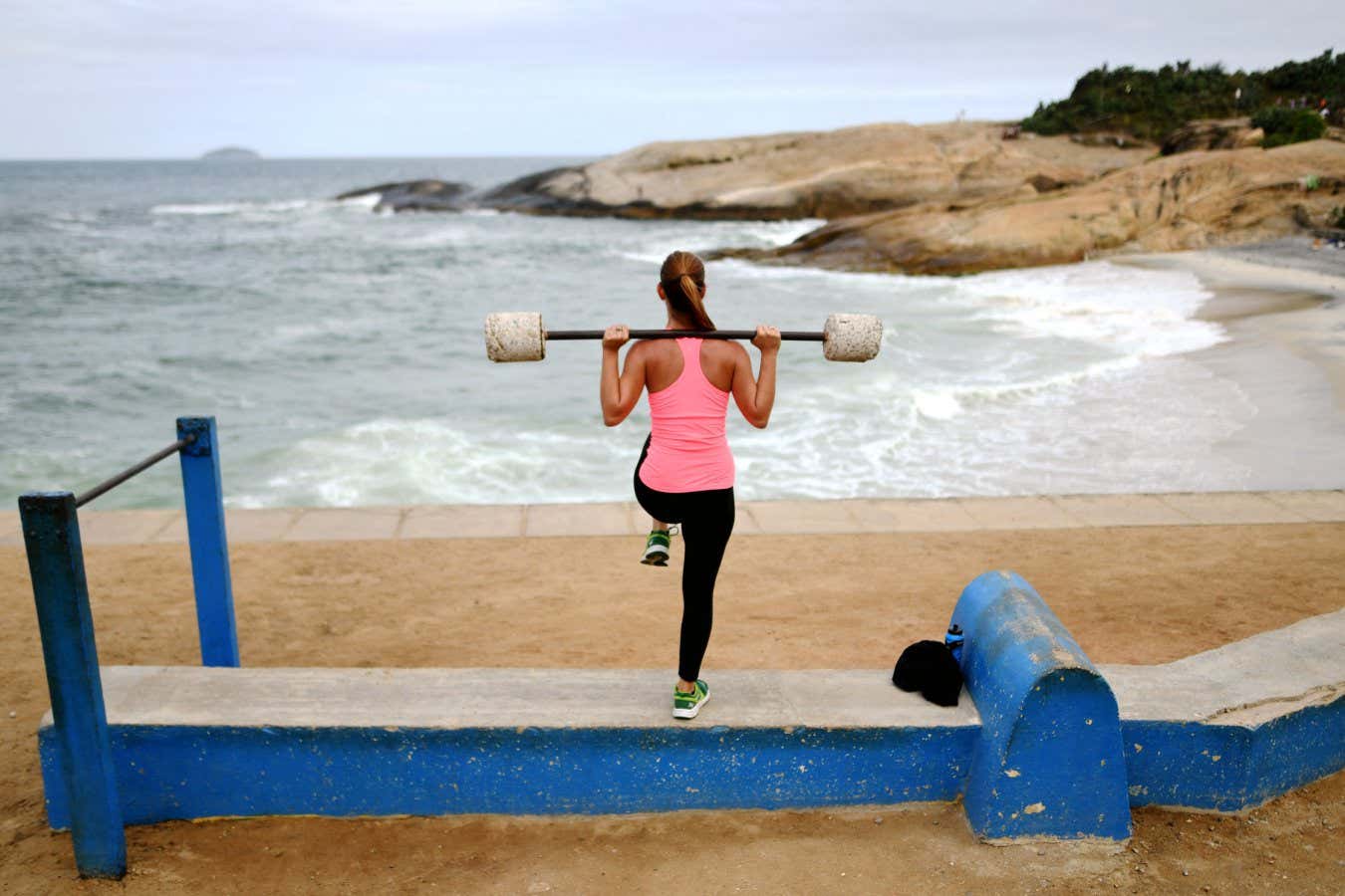 A woman lifts weights as she exercises at an outdoor improvised gym close to Ipanema beach in Rio de Janeiro on August 3, 2016. The Rio 2016 Olympic and Paralympic Games will be held in Brazil from August 5-21 and September 7-18 respectively. (Photo by Kirill KUDRYAVTSEV / AFP) (Photo by KIRILL KUDRYAVTSEV/AFP via Getty Images)