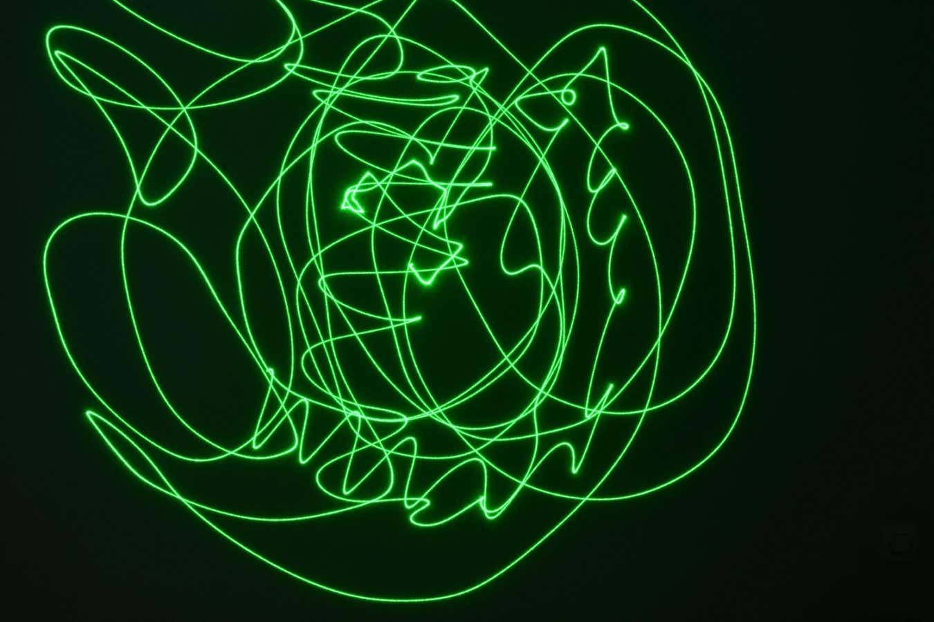Green streaks against a dark background, created by a long exposure image of moving laser beam
