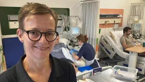 Nicola Alderson stood in the Anthony Nolan Cell Collection Centre at Nottingham's Queens' Medical Centre. She is the charity's Chief Operating Officer.  Behind her two donors are giving stem cells to be sent off for transplant to unrelated recipients