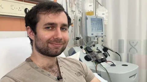 BBC Jordan a 28 year old stem cell donor from London lying on a bed in the new collection centre in Nottingham. He is linked up to a machine which his blood goes through more than two times and extracts millions of stem cells. 