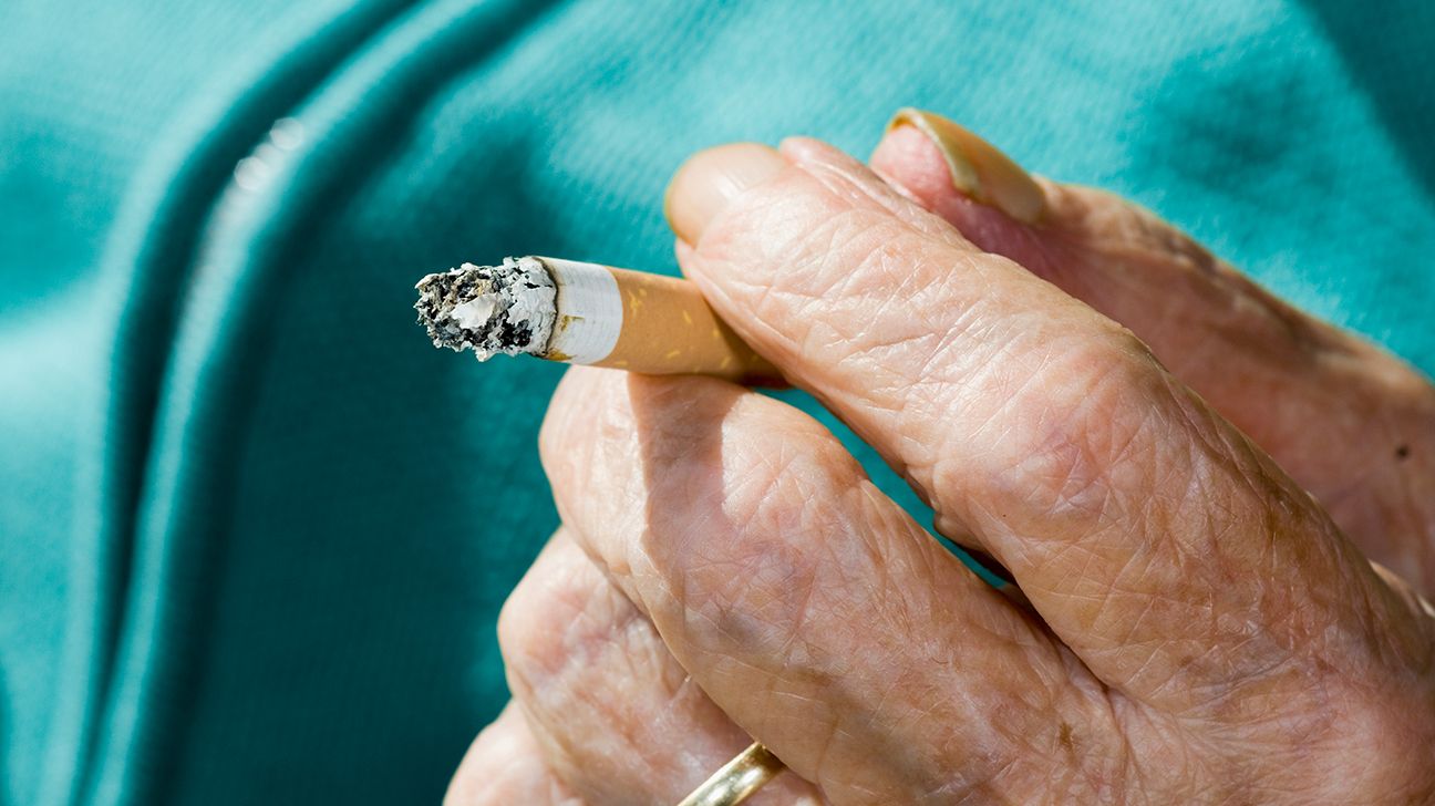 Close up older person hand holding cigarette