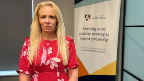 A woman with long blonde hair and a red floral dress 