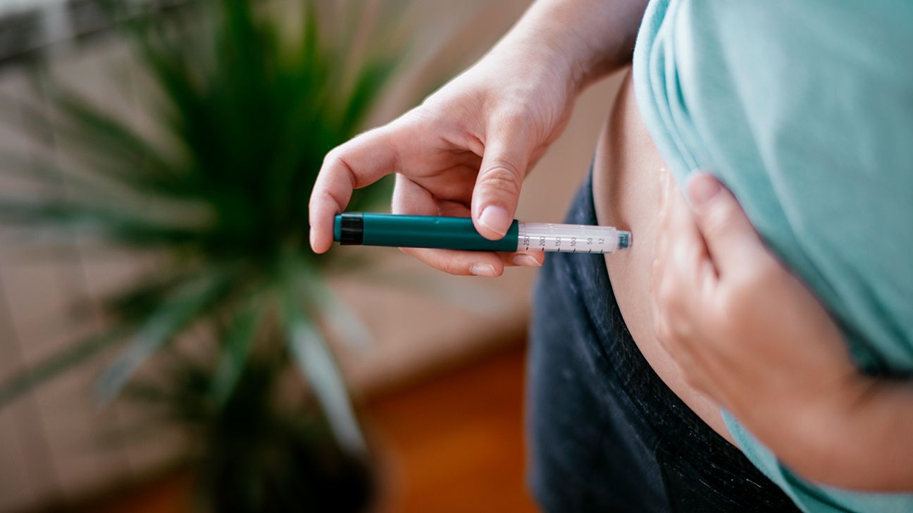 Female using insulin injection pen in abdomen