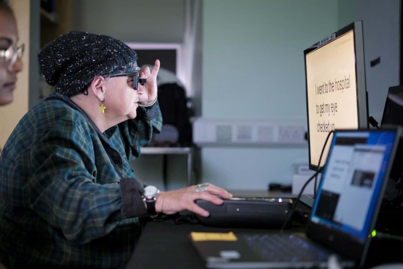 A study partipant wearing the glasses and testing her reading after being fit with the retinal implant