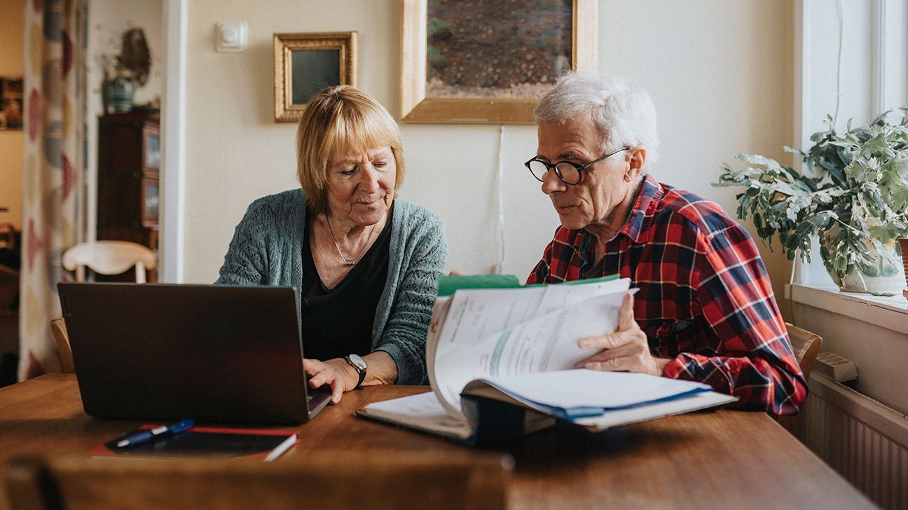 Older couple with laptop and paperwork at table