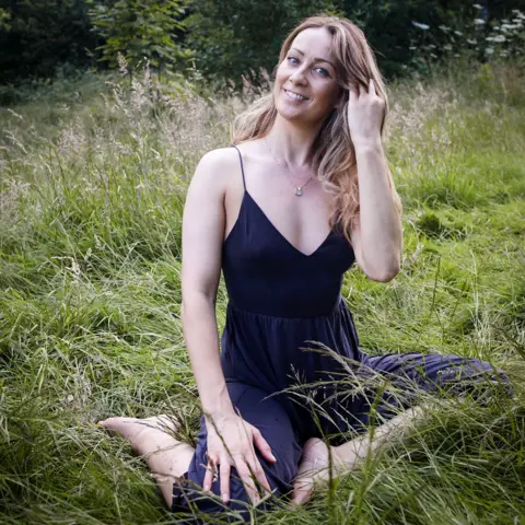 @cariad.connection Eirian Collinge sitting outside in a park