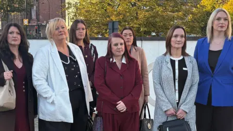 PA Media Seven of the eight nurses standing outside the tribunal centre in Newcastle. They are wearing smart outfits and serious expressions.