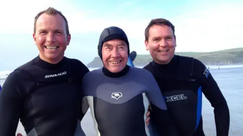 English family Sir Terence (middle) with his sons either side of him. They are all wearing wet suits. 