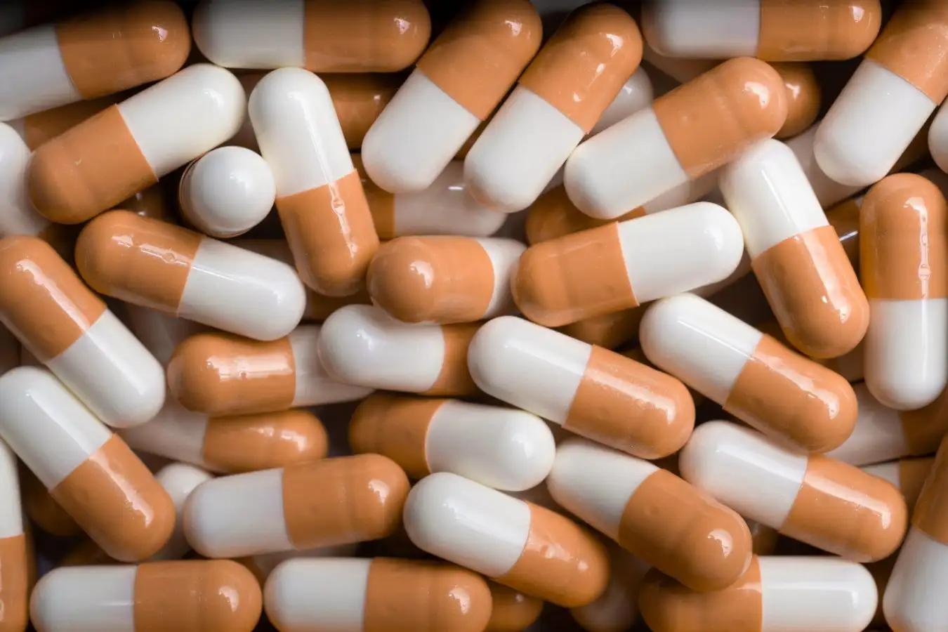 Orange and white capsule pills, viewed from above