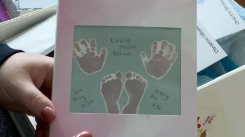 A paper frame of Louie's handprints and footprints with his full name, date of birth and his weight in grams and ounces