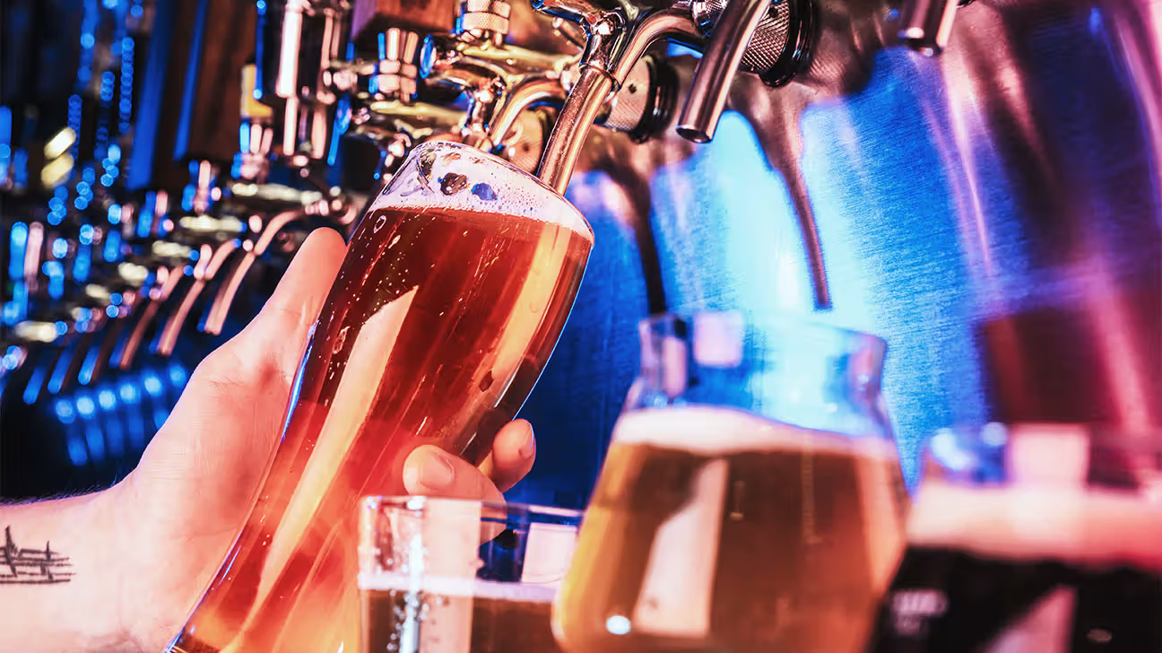 Person filling a glass of beer at a bar