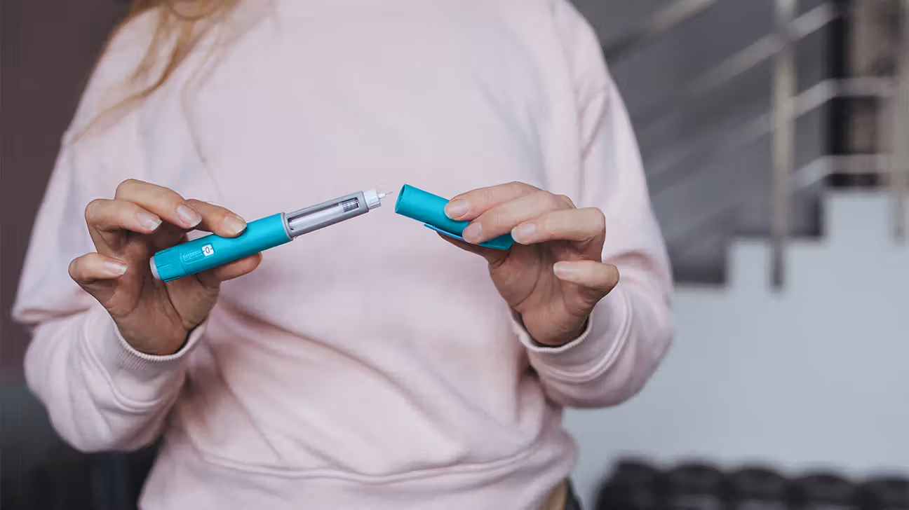 Female holding GLP-1 injector pen