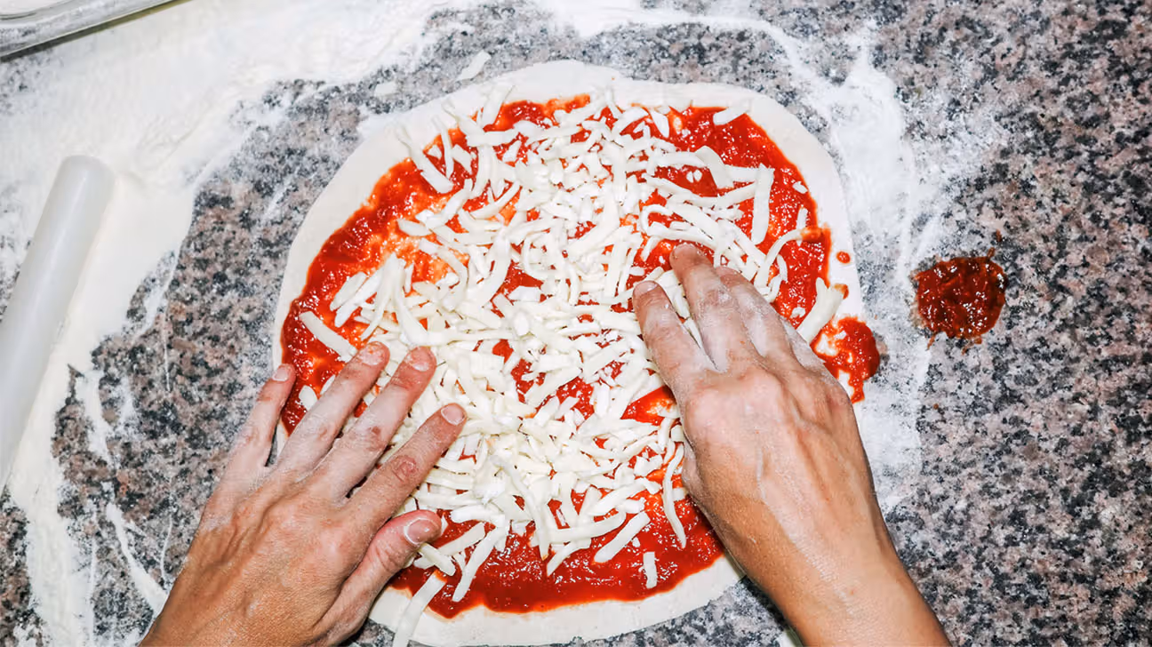 Shredded mozzarella cheese on unbaked pizza