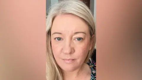 Marie Brown A woman, pictured from the shoulders up, with long blonde hair. There is a blur on either side of the image. 