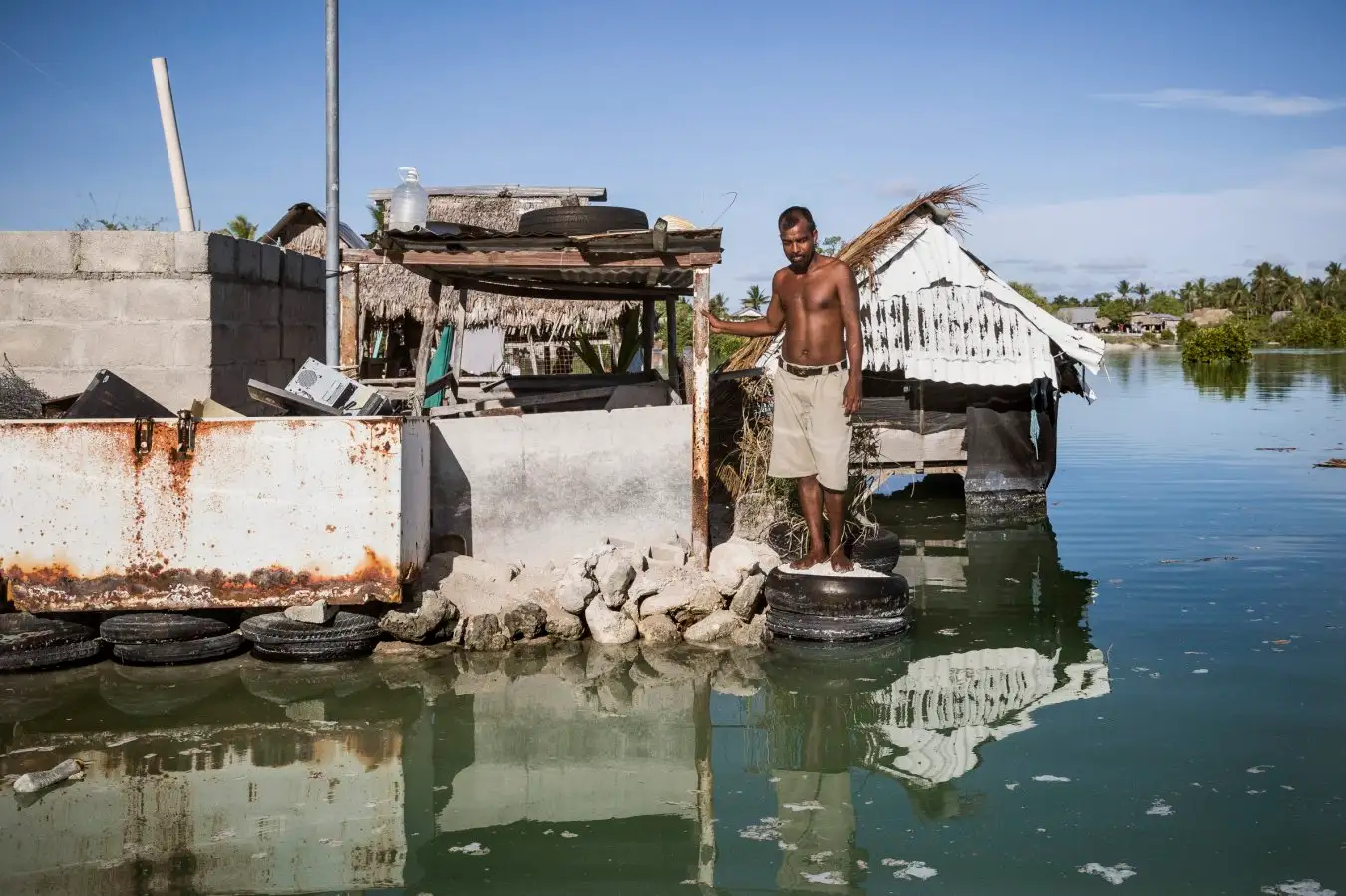 A man standing by his flooded home