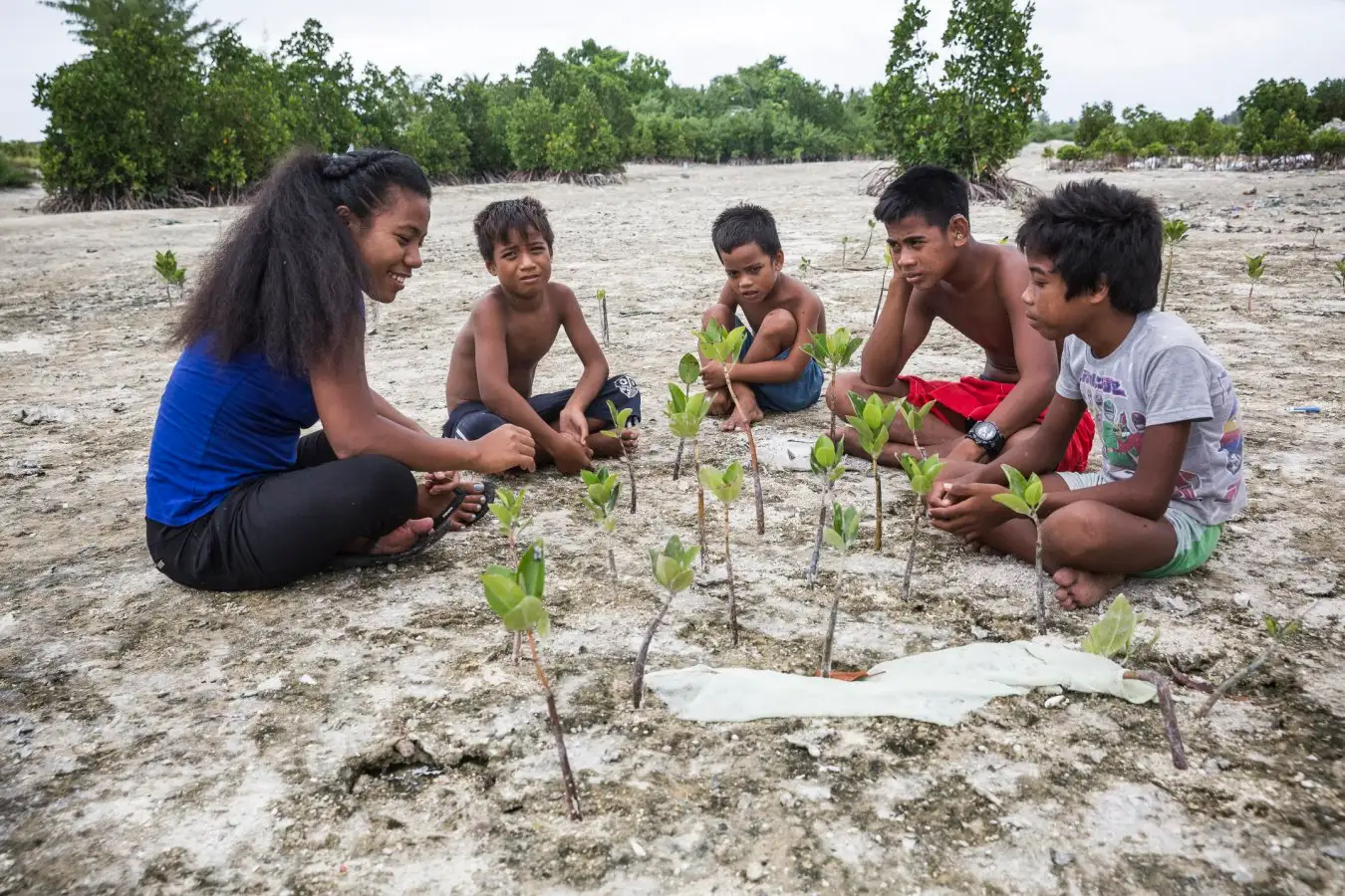 A climate activist in Kiribati teaching local children about mangroves