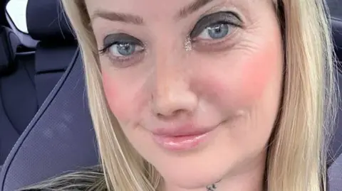 Leanne Abeyance A woman with blonde hair with a blue car seat behind her