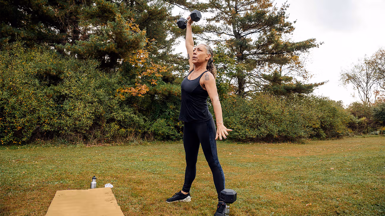 Older female strength training with weights outdoors