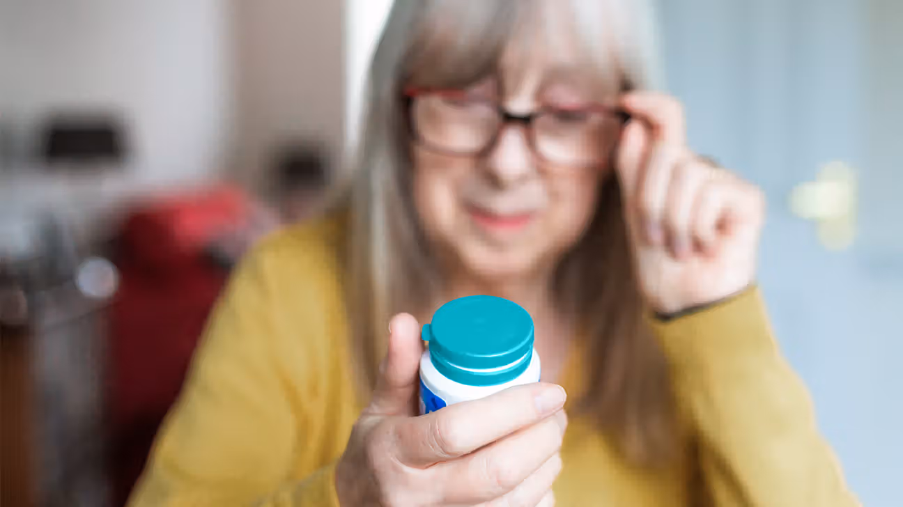 Older female examines bottle of aspirin