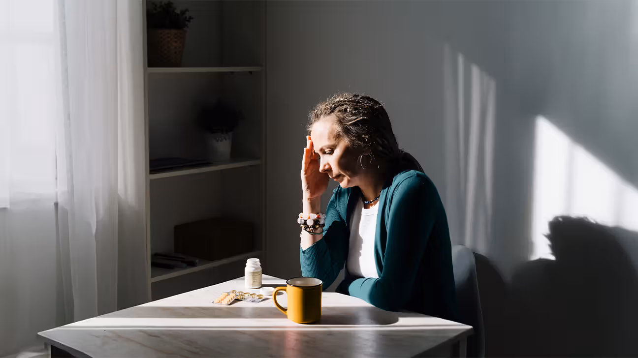 Female sitting at a kitchen table with medications in front of her