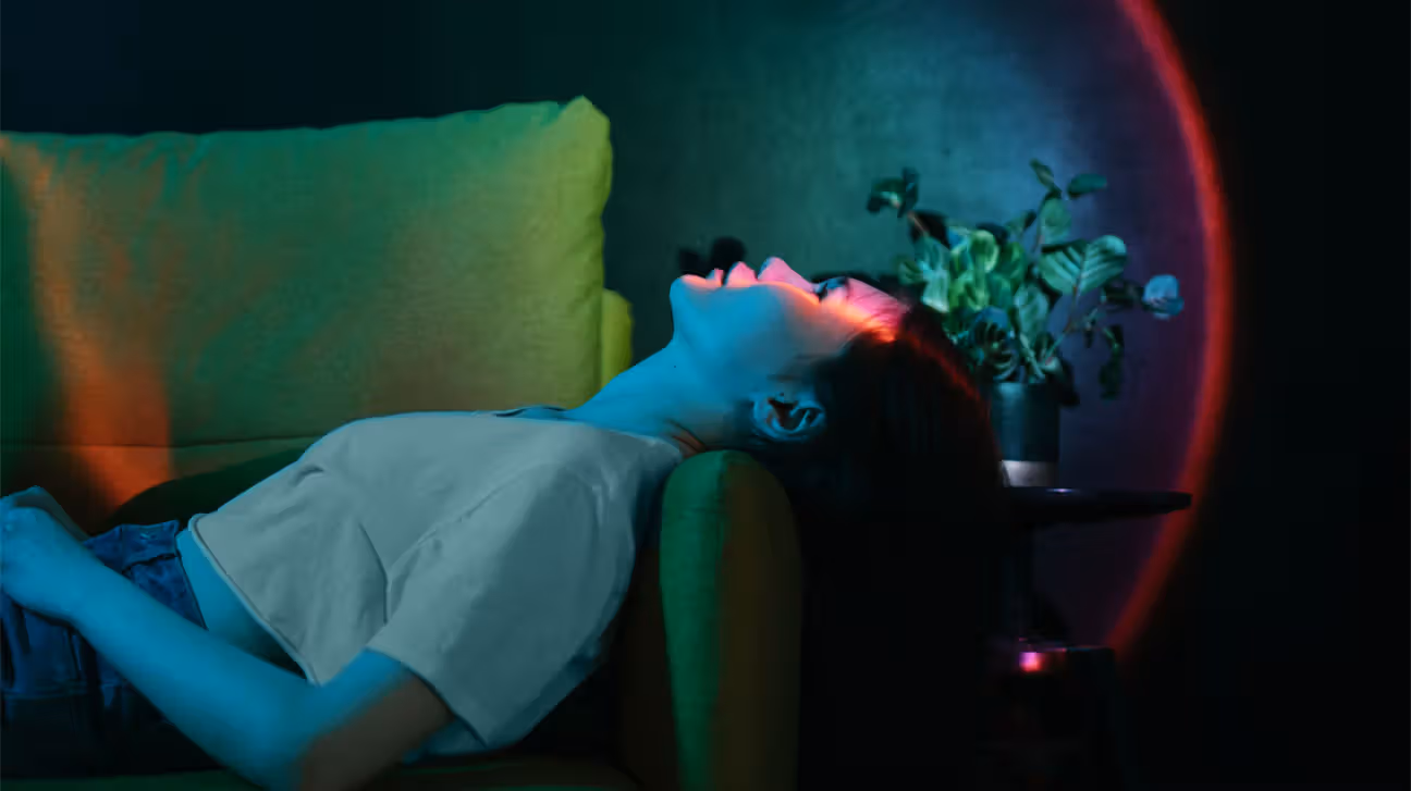 Person laying on a sofa with a light on their face