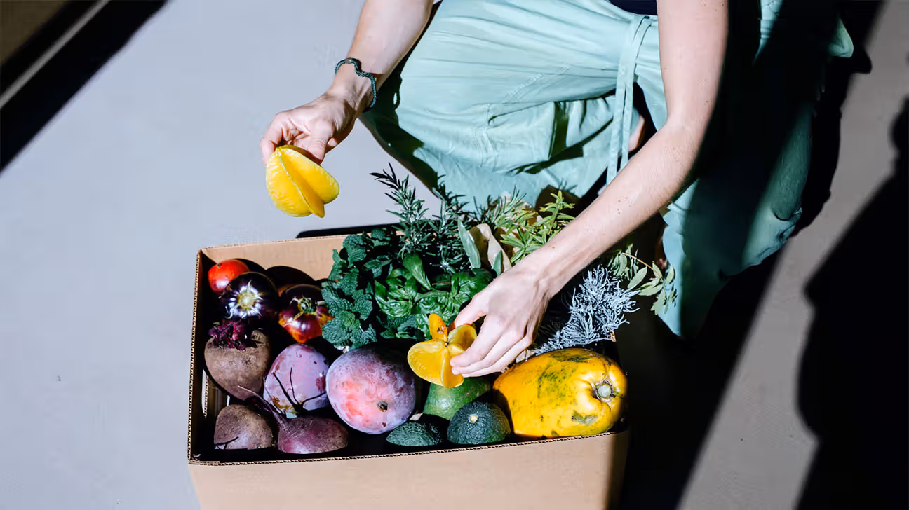 Person sorting through a box of vegetables