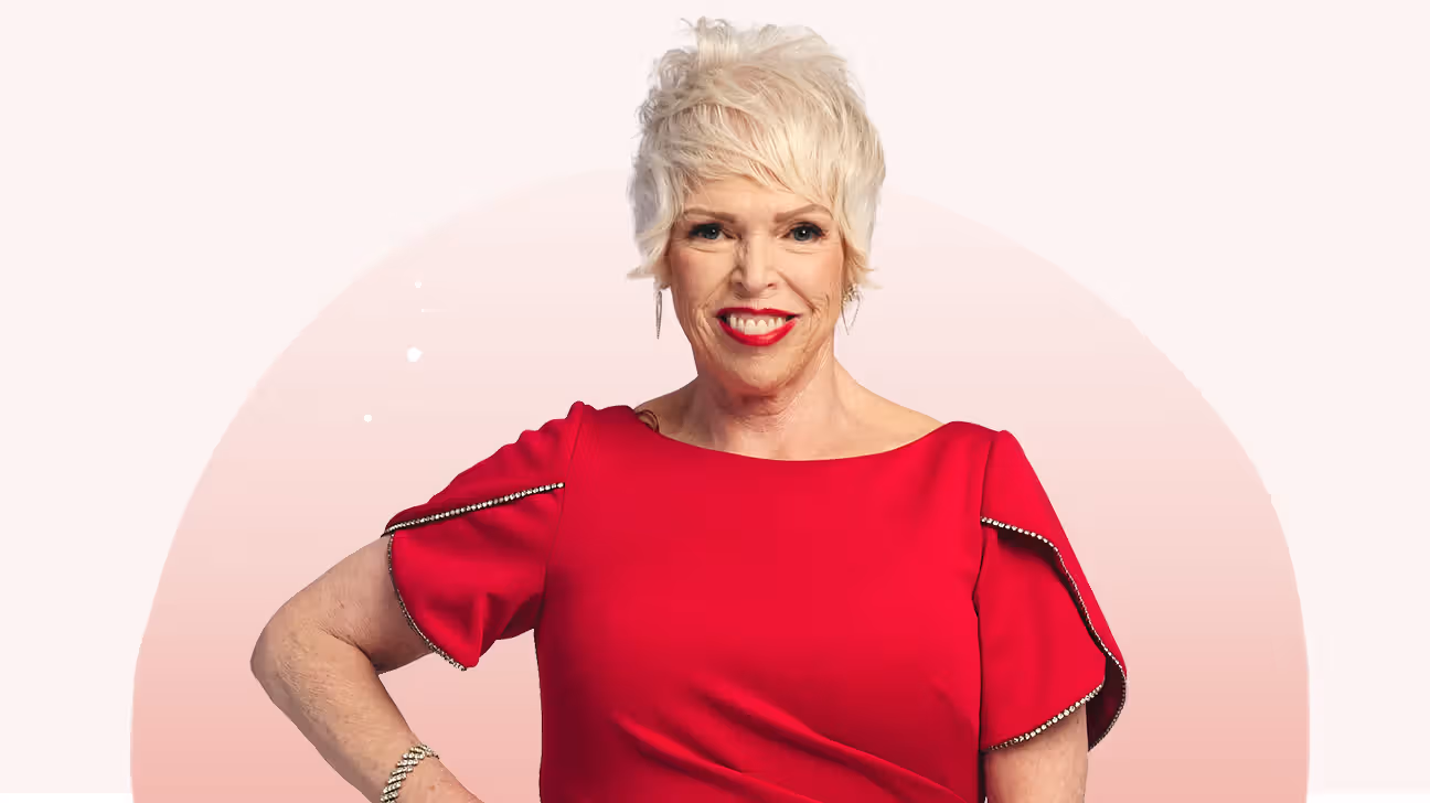 Lori in a red dress, smiling with her hand on her hip