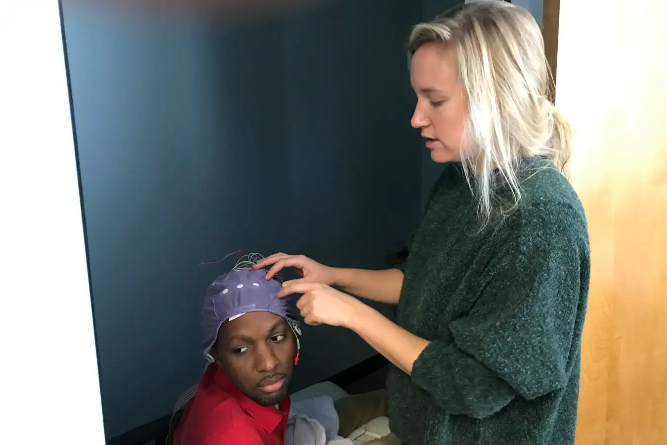 Researcher Karen Konkoly prepares a participant for the study by fitting a cap to their head that records their brain activity