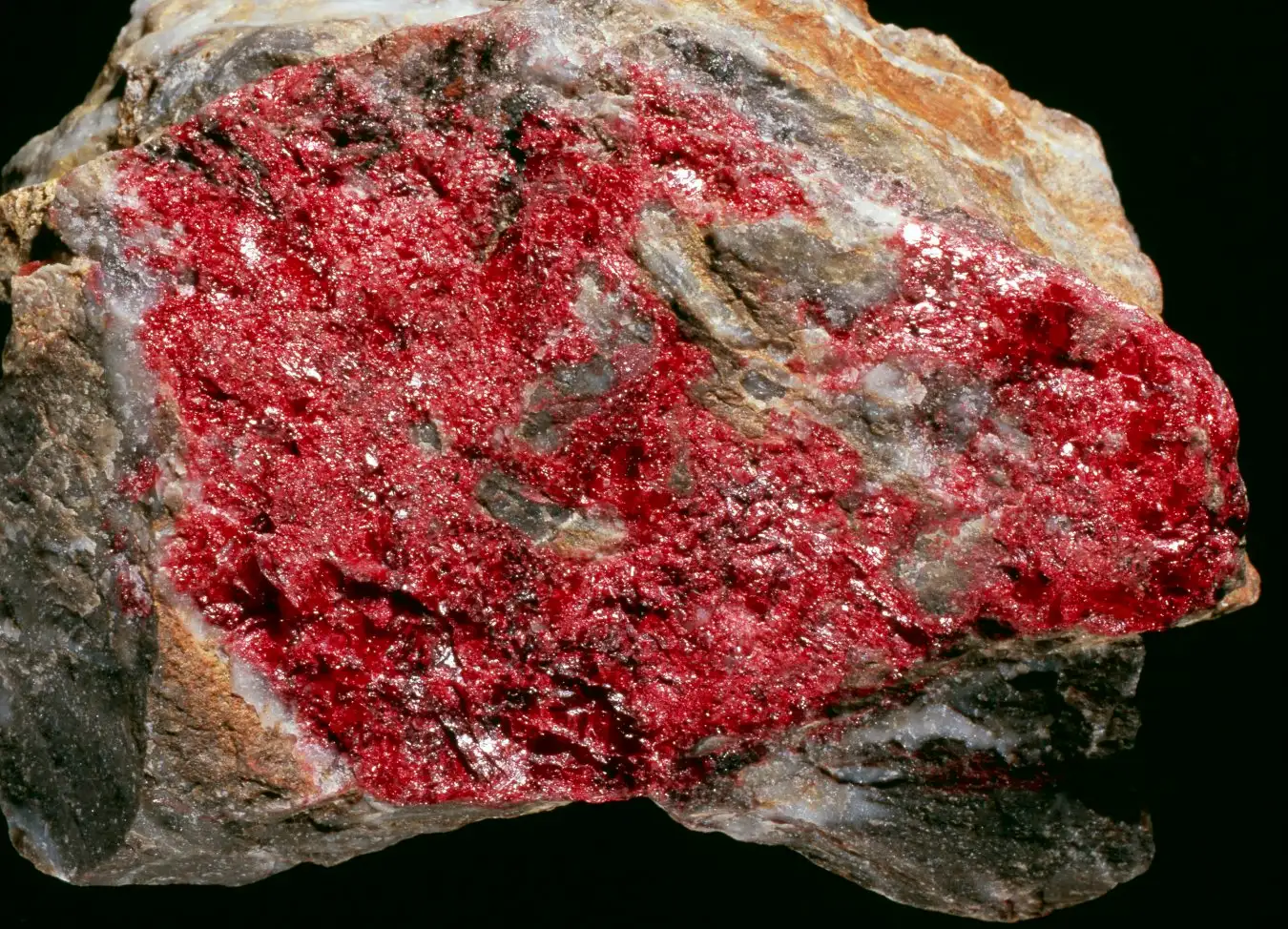 Cinnabar. Red deposits of the cinnabar in a sample of a mercury ore. Cinnabar is a mercury sulphide (HgS), and is the most common ore for the extraction of mercury. It is usually found in veins associated with recent volcanism, but is also deposited near hot springs. Mercury is a liquid metal used in industry and in equipment such as thermometers.