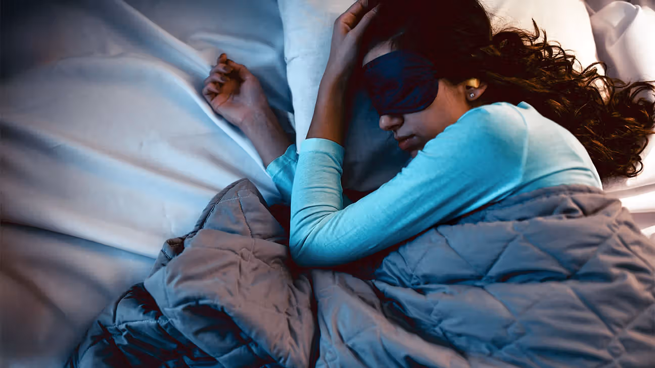 Person sleeping in bed with a sleep mask and earplugs