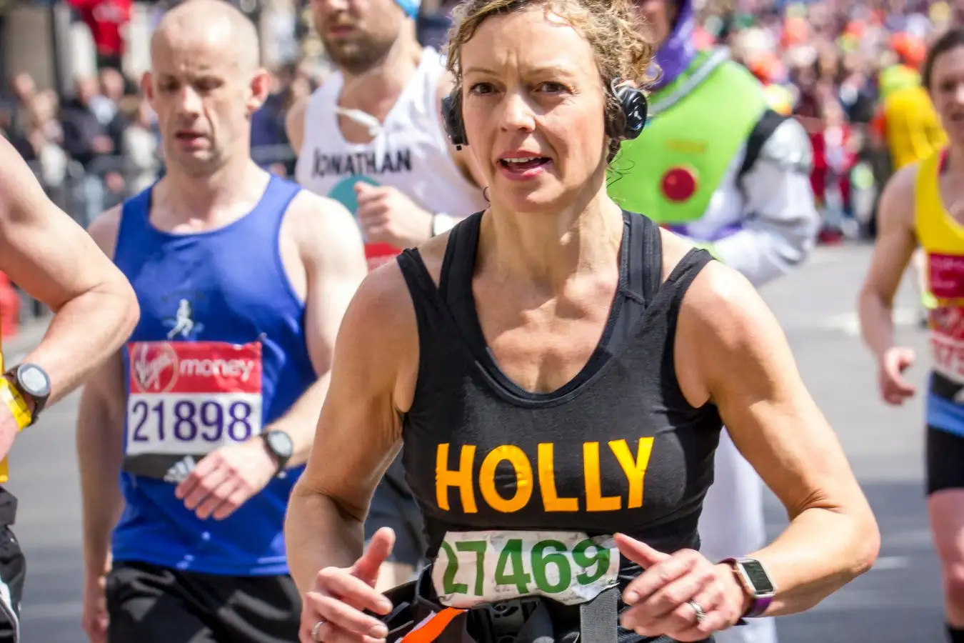 A woman wearing headphones while running a marathon