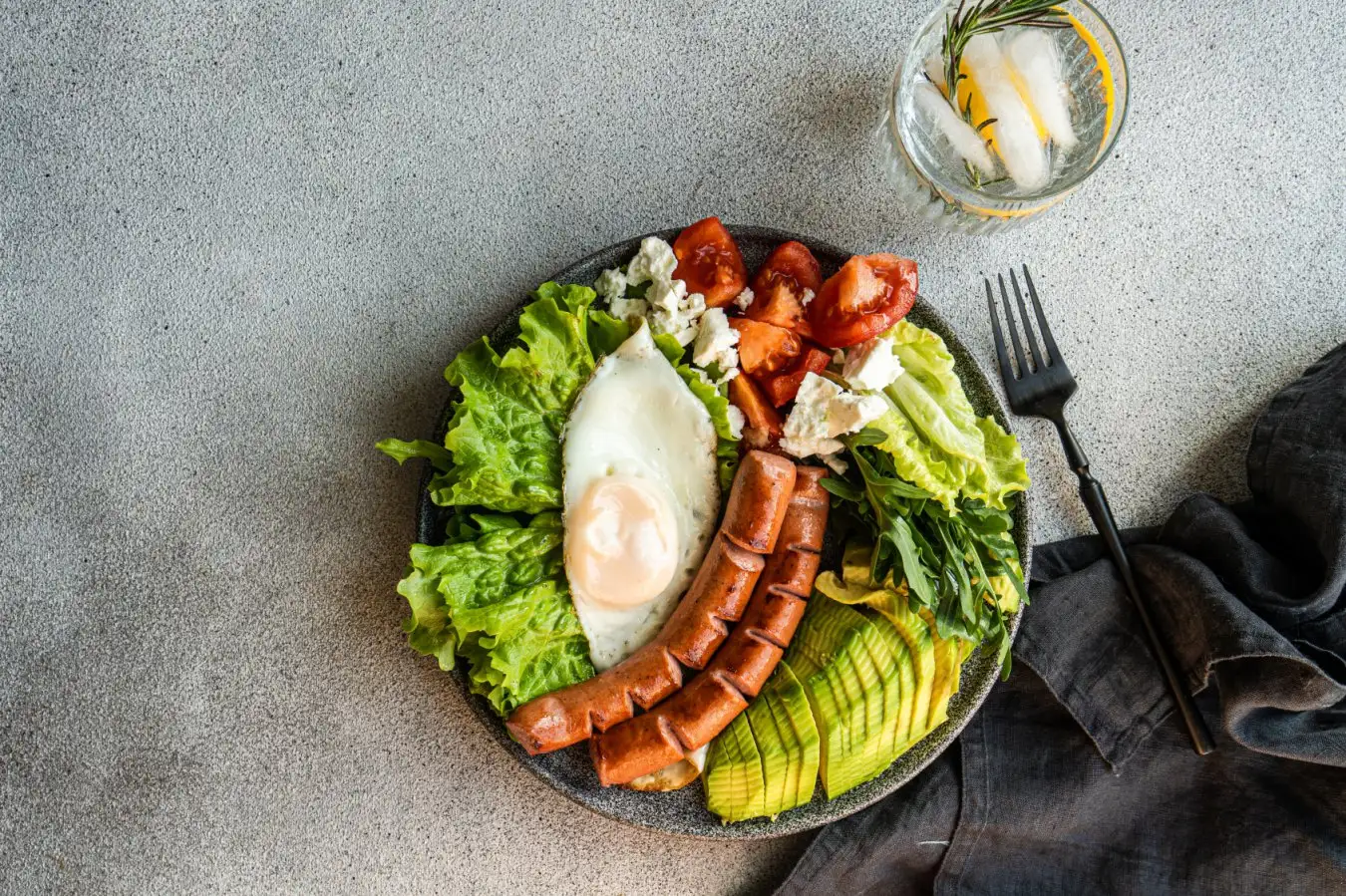 healthy ketogenic lunch plate with vegetables, fried egg and sausages