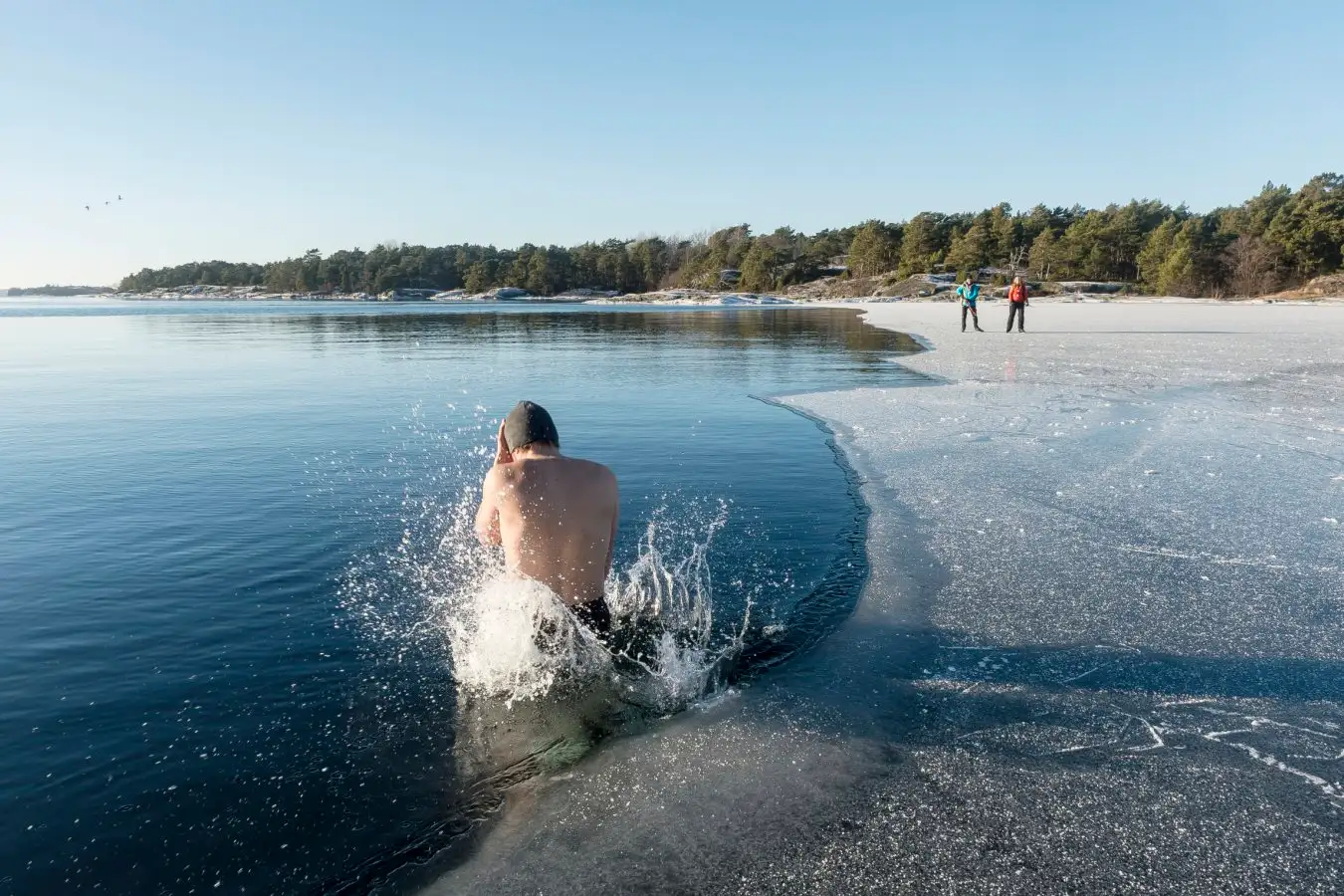A man takes a cold plunge in a frozen lake