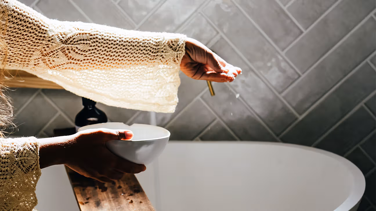 Female wearing crochet sweater with bowl in bathroom