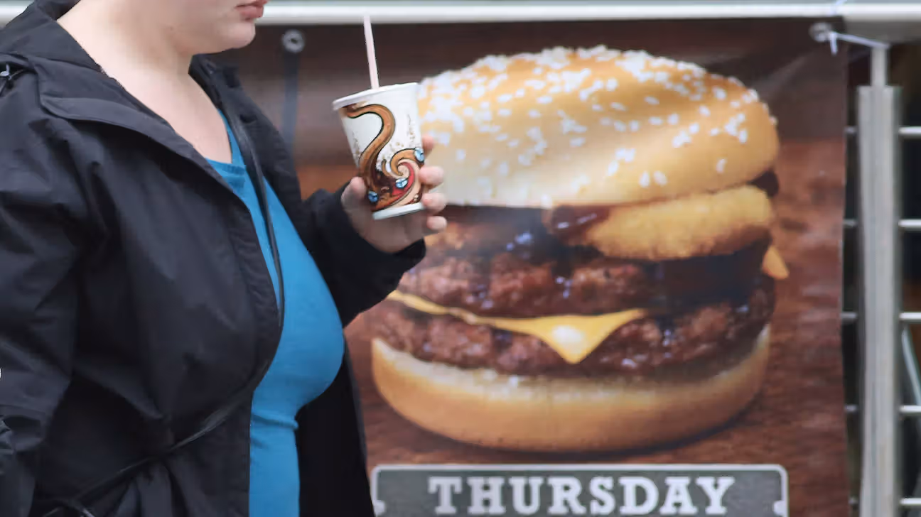 Person walking past a sign advertising a hamburger