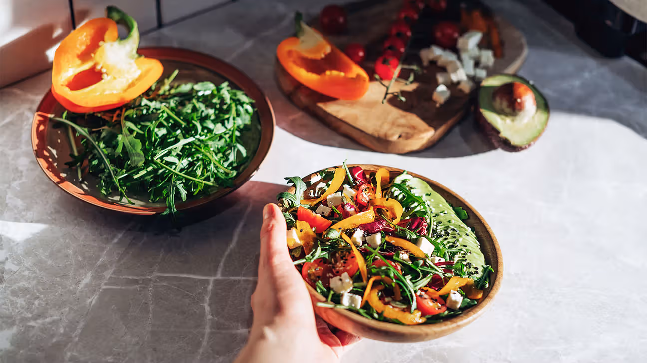Female hands holding salad bowl with veggies