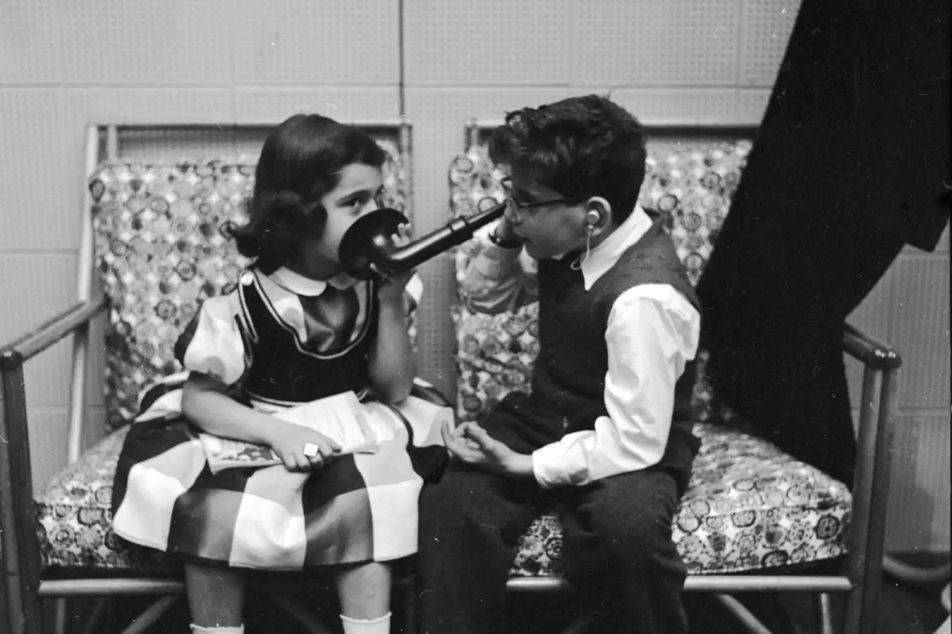 1955: Two friends at a League school for children with impaired hearing, experiment with an old-fashioned ear trumpet. In contrast to this cumbersome device, they are fitted with minuature hearing aids, barely visible inside the ear. (Photo by Vecchio/Three Lions/Getty Images)