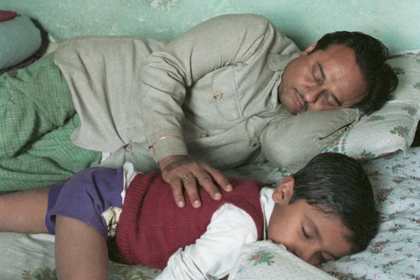 A man sleeping next to his son. Humans sleep far less than an ape like us ought to