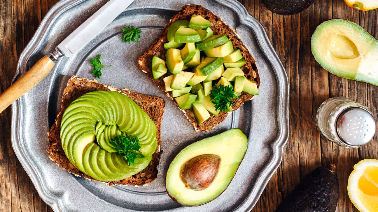 A plate with half an avocado and two slices of avocado on toast