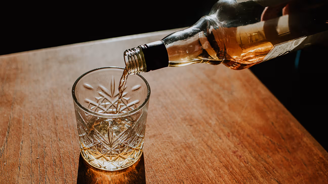 Pouring whisky from a bottle into a crystal glass