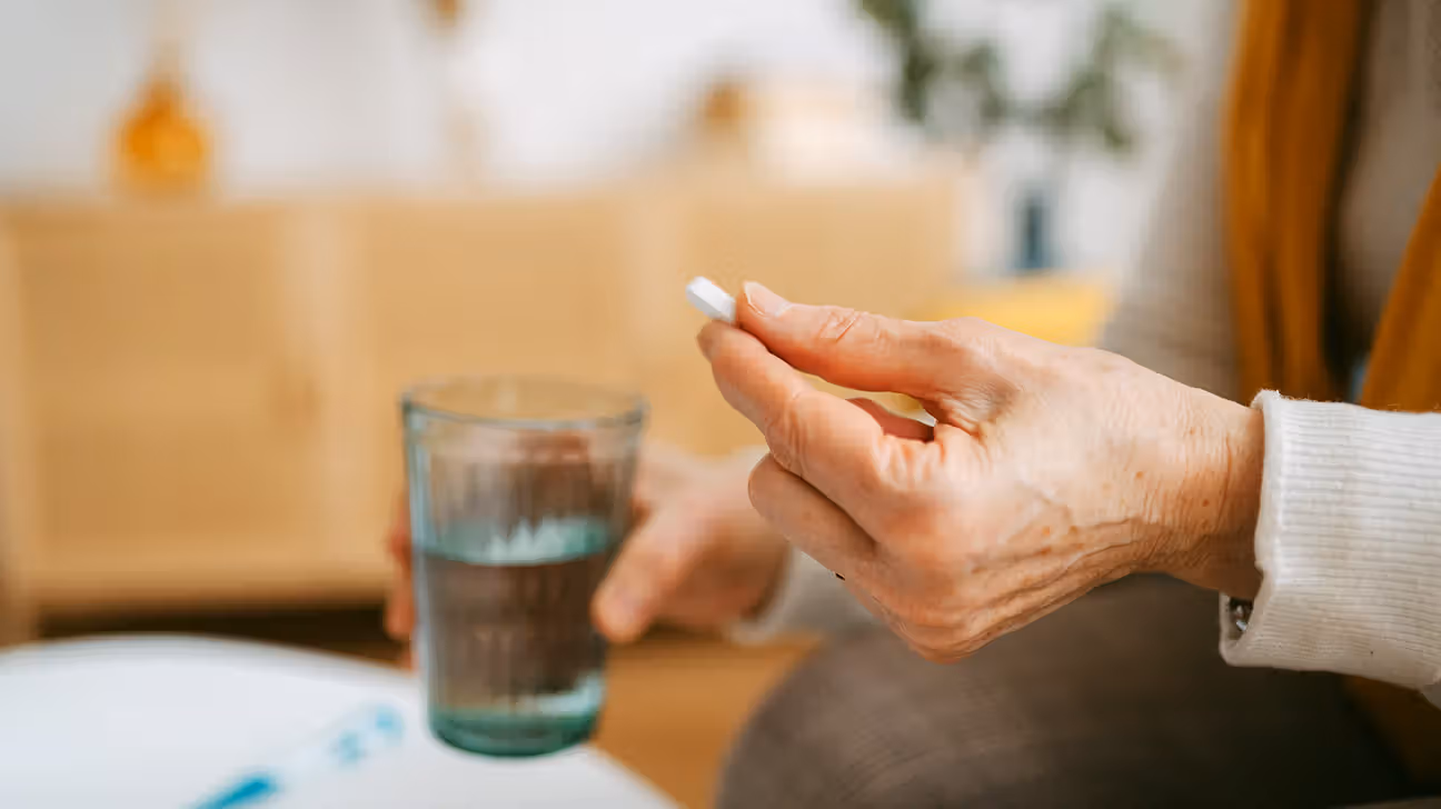 Older female holding pill and glass of water