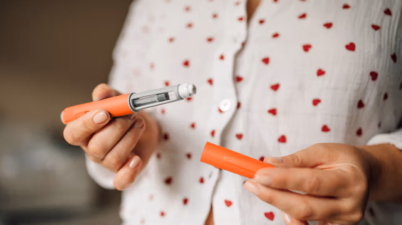 Female holding a GLP-1 pen in front of her
